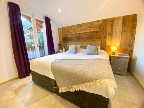 a bedroom with a large bed with a wooden wall at Les Trois Pointes in Morzine