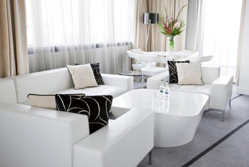 a white living room with white couches and a table at Crowne Plaza Manchester City Centre by IHG in Manchester
