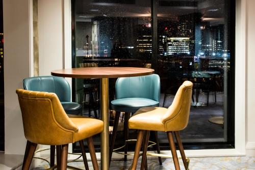 a table and chairs in front of a window at Crowne Plaza Manchester City Centre by IHG in Manchester