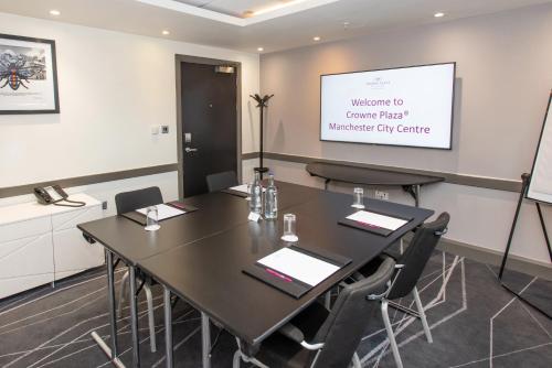a meeting room with a table and a projector screen at Crowne Plaza Manchester City Centre by IHG in Manchester