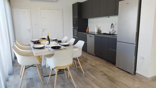 eine Küche mit einem Esstisch und weißen Stühlen in der Unterkunft Villa Nika in Peroj