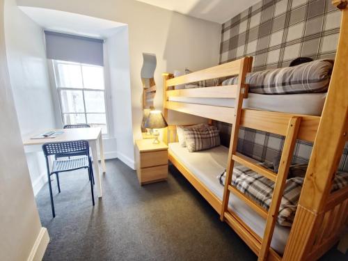 a bedroom with two bunk beds and a desk at Edinburgh Backpackers - over 18s only in Edinburgh