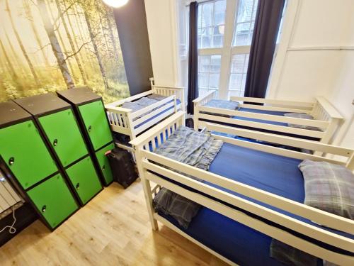 three bunk beds in a room with a window at Edinburgh Backpackers - over 18s only in Edinburgh