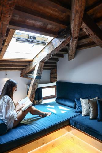 a woman sitting on a couch reading a book at Santa Croce Boutique Hotel in Venice