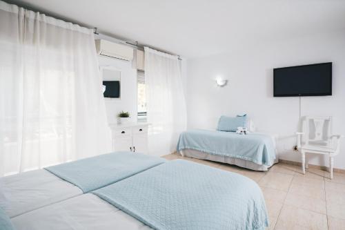 a bedroom with two beds and a flat screen tv at Mare Estepona Hotel in Estepona