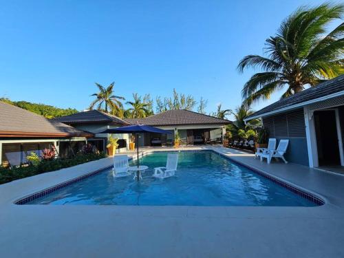 a swimming pool with chairs and a house at Villa Fantasy private beach and private pool in Rio Bueno