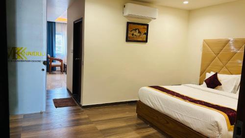 a bedroom with a bed and a door to a hallway at MK Naidu Hotel &Conventions Center in Warangal
