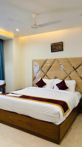 a bedroom with a large bed with a wooden headboard at MK Naidu Hotel &Conventions Center in Warangal