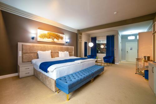 a large bedroom with a large bed and a blue bench at Hotel Nordic Twins & Wellness in Rădăuţi