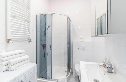 biała łazienka z prysznicem i umywalką w obiekcie Apartament z osobną sypialnią w pięknej kamienicy w centrum we Wrocławiu