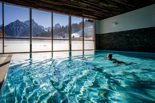 a person swimming in a swimming pool with mountains at Landal Chalet Matin in Bürserberg