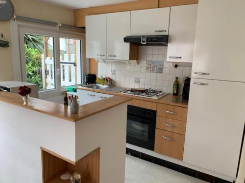 une cuisine avec des armoires blanches et un four à plaques de cuisson dans l'établissement Bray-Dunes avec jardin - 3chambres, à Bray-Dunes
