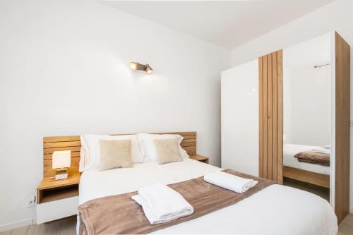 a bedroom with a white bed and a mirror at Monaco Border - Bel appartement rénové - CM in Beausoleil