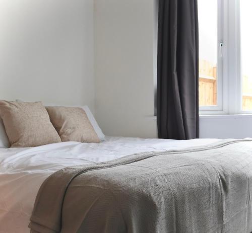 a white bed with two pillows and a window at Alban Suites in St. Albans