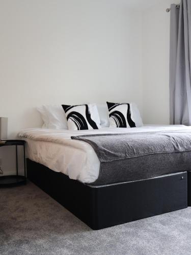 a bed with black and white pillows on it at Alban Suites in St. Albans