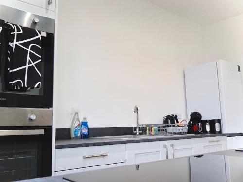 a kitchen with white cabinets and a black appliance at Alban Suites in Saint Albans