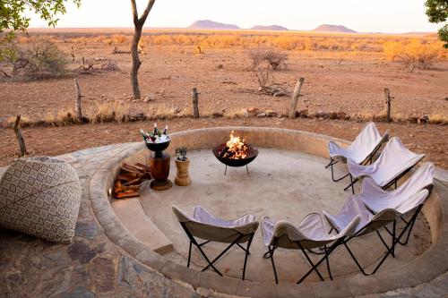 a fire pit with four chairs and a table with a fire burns at Last Word Madikwe in Madikwe Game Reserve