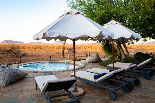 a pool with two umbrellas and lounge chairs next to it at Last Word Madikwe in Madikwe Game Reserve