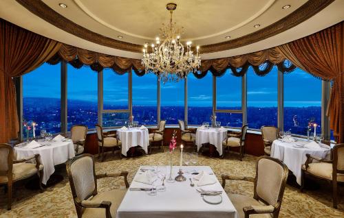 Un comedor con mesas y sillas y una lámpara de araña. en Al Habtoor Grand Beirut, en Beirut
