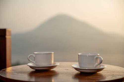 two cups of coffee sitting on a wooden table at Pondok Devana Kintamani in Kintamani