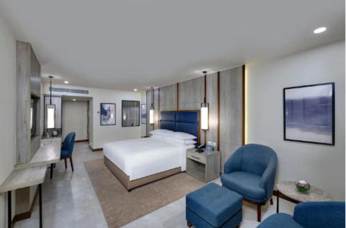 a hotel room with a bed and blue chairs at Pearl Inn Paradise Hotel in Karachi