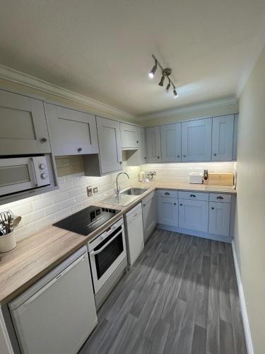 a kitchen with white cabinets and blue appliances at The Osborne Apartments in Torquay