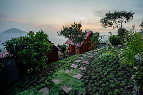 a grassy hill with a house and a pathway at Pondok Devana Kintamani in Kintamani