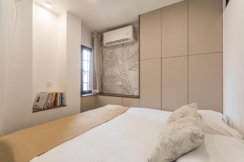 a bedroom with a white bed and a window at Tonight Homestay West Nanjing Road Shanghai in Shanghai