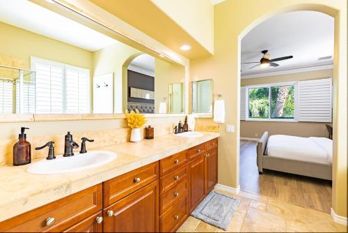 a bathroom with a sink and a large mirror at Mini Golf, Saltwater Pool & Spa by MariamsBnb in Desert Hot Springs
