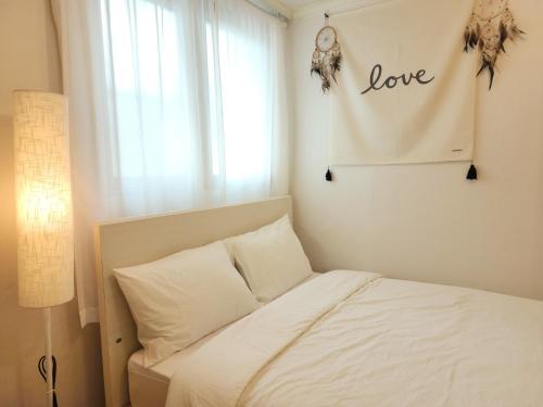 a bedroom with a bed with a love sign on the wall at Lucy Stay in Seoul
