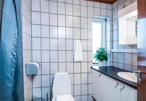 a white tiled bathroom with a toilet and a sink at Hotel Frederikshavn in Frederikshavn
