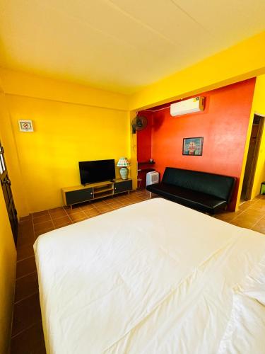 a bedroom with a white bed and a yellow wall at Moondance Cottage Inn in Ko Chang