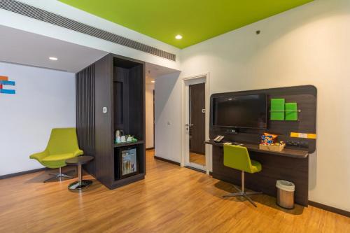 a living room with two green chairs and a flat screen tv at Park Inn by Radisson,South Delhi in New Delhi
