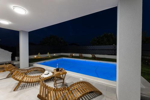 einen Pool in einem Haus mit Stühlen und einem Tisch in der Unterkunft Vila MaMe in Kaštela