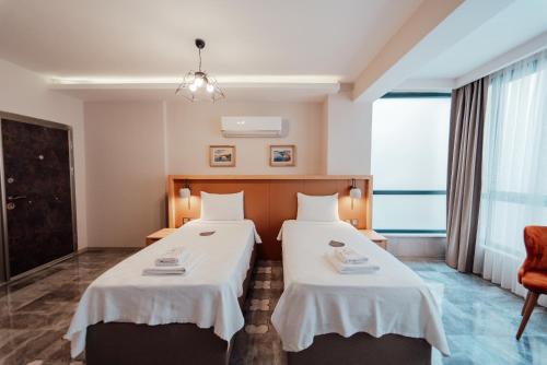 a hotel room with two beds and a chair at Fortunella Suites in Finike