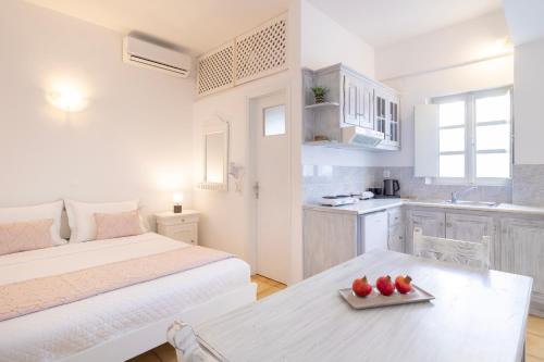 a white room with a bed and a table with apples on it at Vrachia Studios & Apartments in Oia