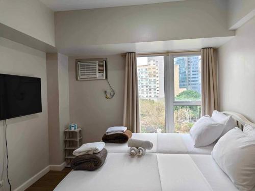 a bedroom with a large white bed with a window at Solinea T3 805-A Elegant studio in Cebu City