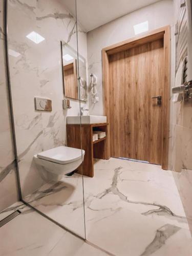 a bathroom with a toilet and a glass shower at La Park Aparthotel in Kudowa-Zdrój