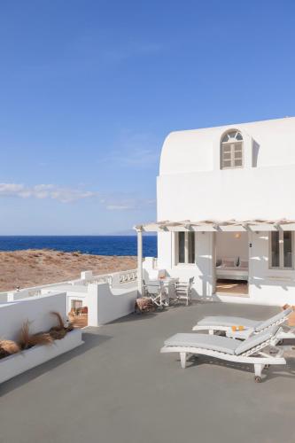 a white house with the ocean in the background at Vrachia Studios & Apartments in Oia