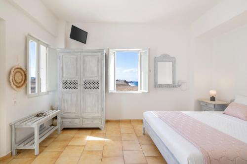 a white bedroom with a bed and two windows at Vrachia Studios & Apartments in Oia