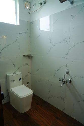 a white toilet in a bathroom with marble walls at Pinnacle Resort Vagamon in Vagamon