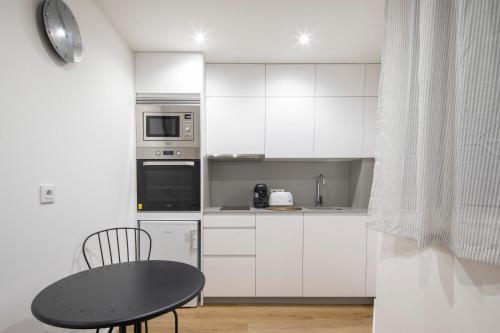 a kitchen with white cabinets and a black table at Garo in Vigo