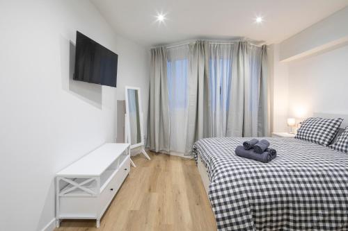 a white bedroom with a bed and a tv at Garo in Vigo