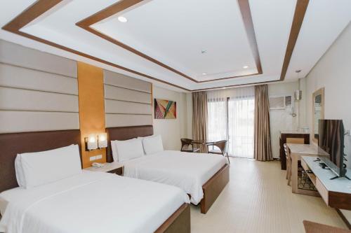 a hotel room with two beds and a television at Cebu Westown Lagoon - South Wing in Cebu City