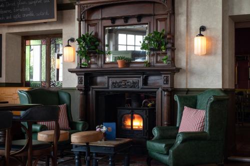 a bar with green chairs and a fireplace at The Brewers Inn in London