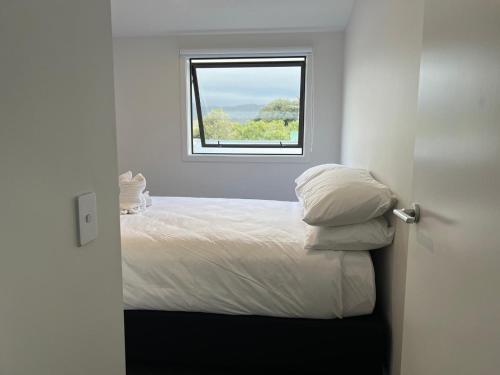 a white bedroom with a bed with a window at Central Modern 3-Bedroom,3- Bathroom House with Patio and Carpark- Lower Hutt City Centre in Lower Hutt