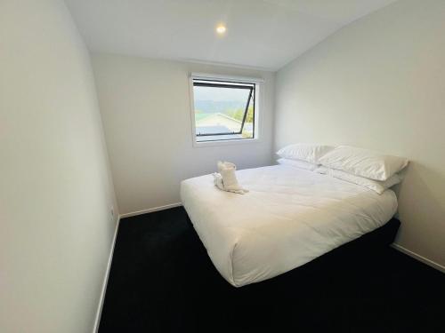 a small bedroom with a white bed with a window at Central Modern 3-Bedroom,3- Bathroom House with Patio and Carpark- Lower Hutt City Centre in Lower Hutt