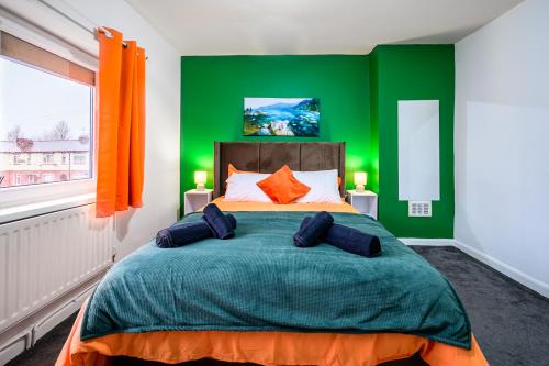 a bedroom with a green wall and a bed with pillows at Trafford Eden - 3 Bed Home near Old Trafford and Trafford Centre with Free Parking in Manchester