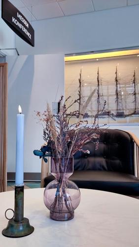 a candle and a vase with flowers on a table at Hotel Frederikshavn in Frederikshavn