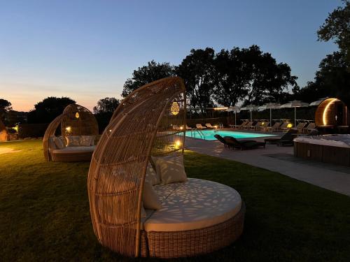 a wicker chair sitting in the grass next to a pool at Antica Fonte Holiday Homes in San Pantaleo